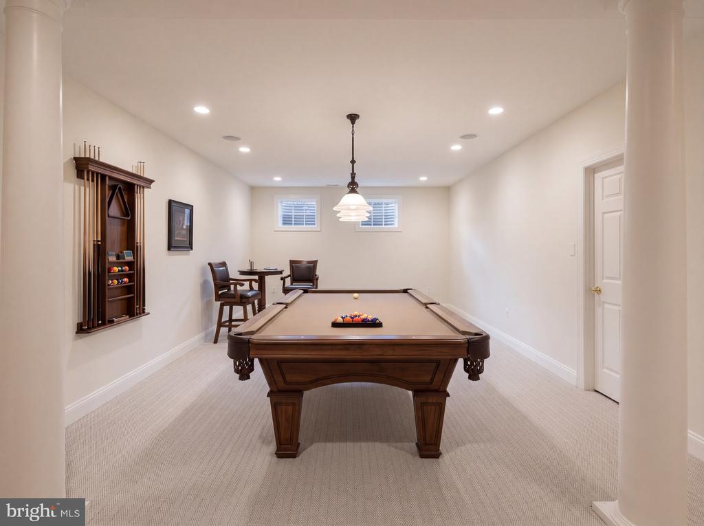 Billiard room with a brown pool table and wall-mounted cue rack.