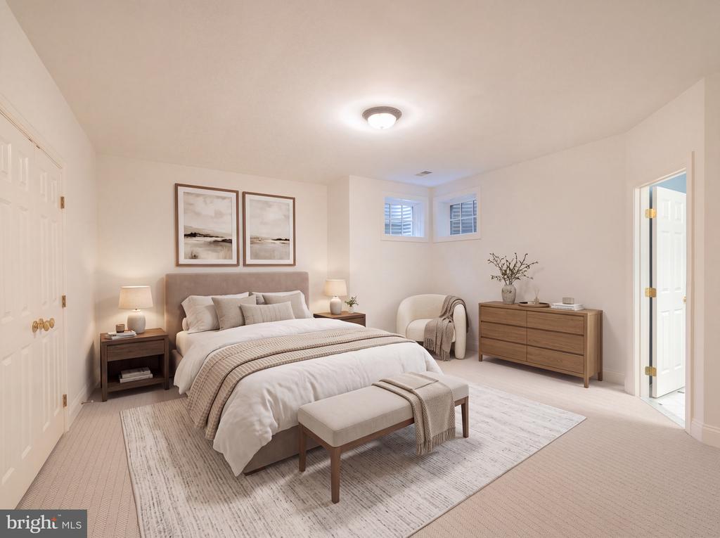 Staged bedroom with a white bed, framed artwork, a dresser, and an upholstered bench at the foot.