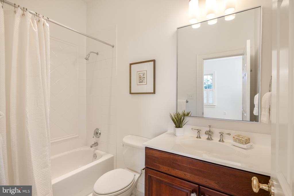 Bathroom with a curtained tub, toilet, and dark wood vanity beneath a large mirror.