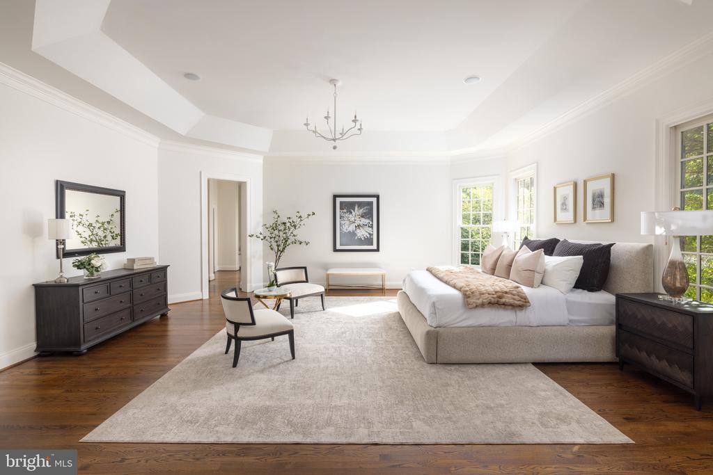 Living room with a white sectional, pale rug, dark wood floors, and large daylight-filled windows.