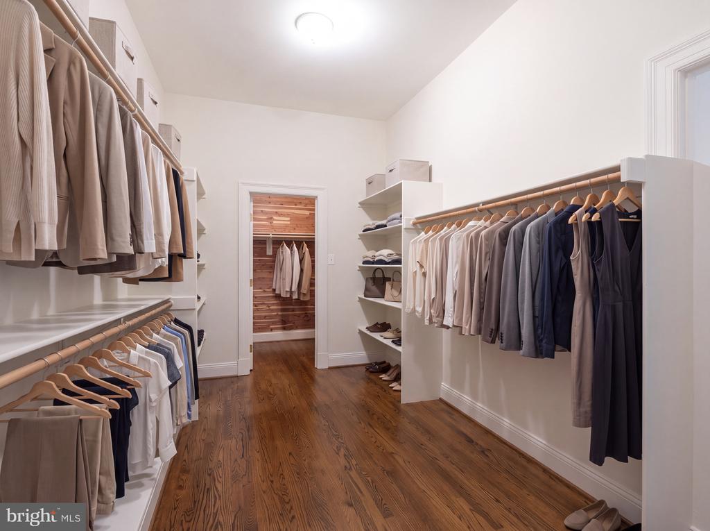 Walk-in closet with clothing on both sides, white built-ins, and a doorway to a cedar-lined closet.
