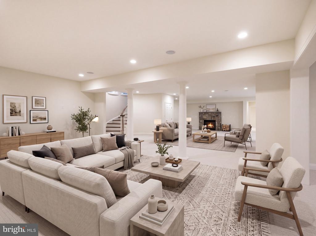 Staged lower-level living room with seating areas, a staircase, and a lit fireplace.