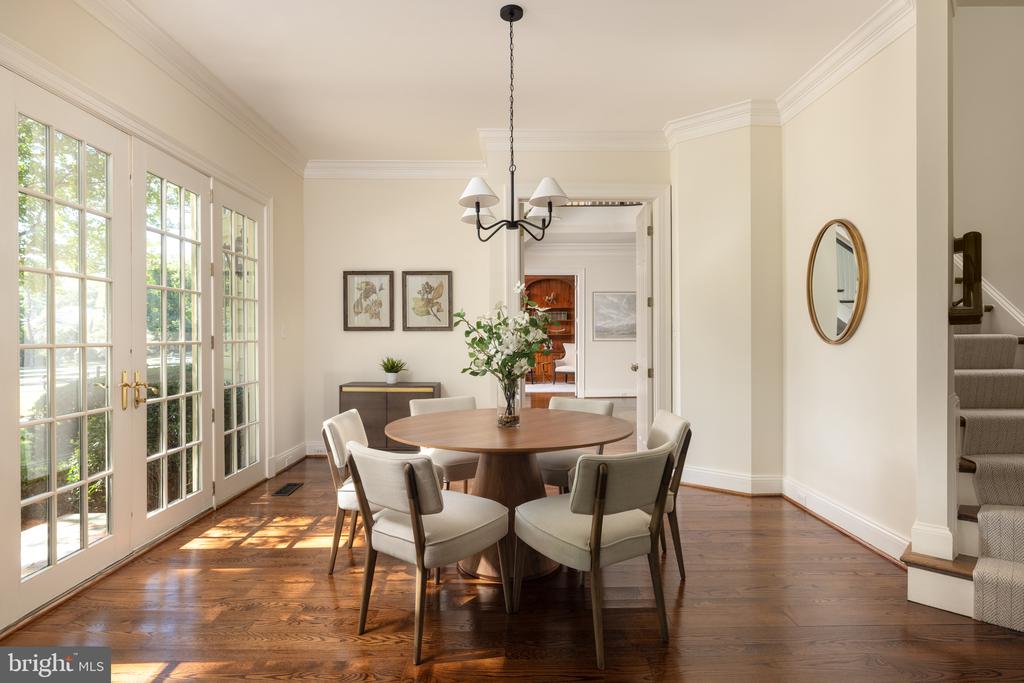Dining room with a round table, chandelier, hardwood floors, and tall French doors.