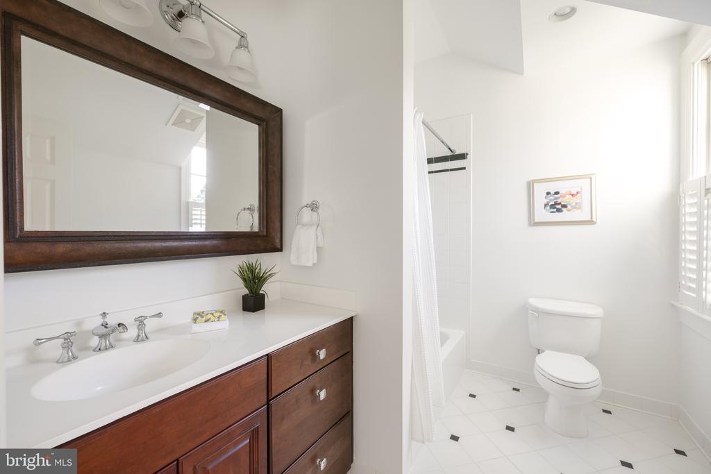 Bathroom with a wood vanity, large framed mirror, and toilet beside a curtained tub-shower.