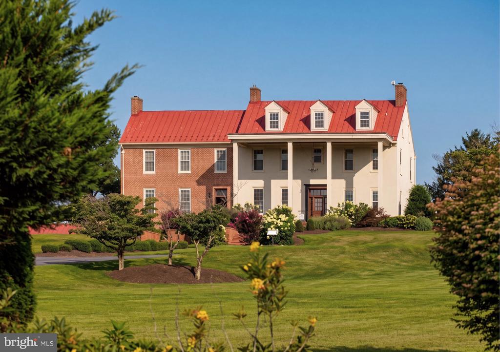 Large brick and stucco building with a red metal roof, covered entrance, and landscaped lawn.