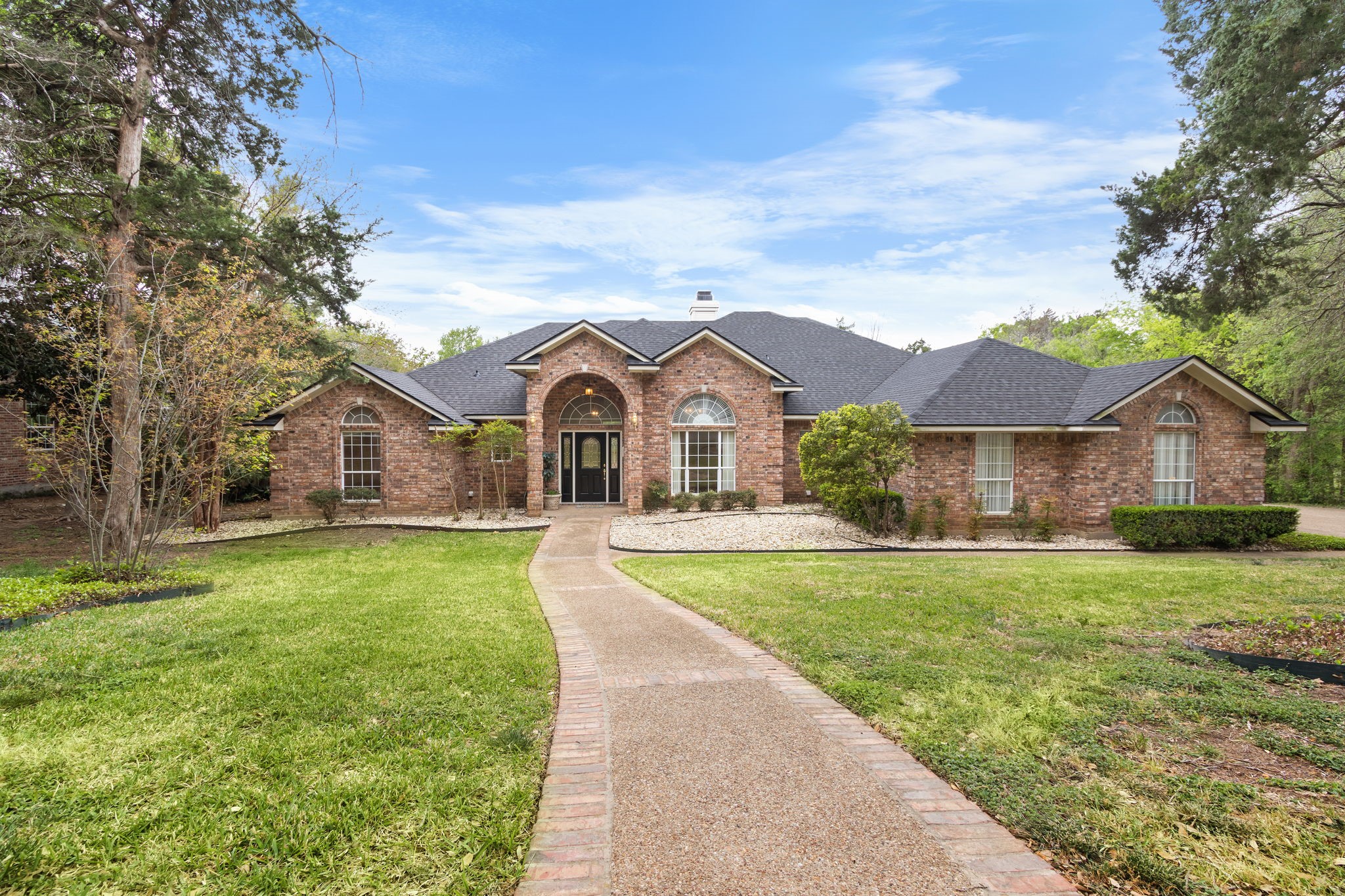 Red brick house with an arched entrance and a curved walkway across the front lawn.