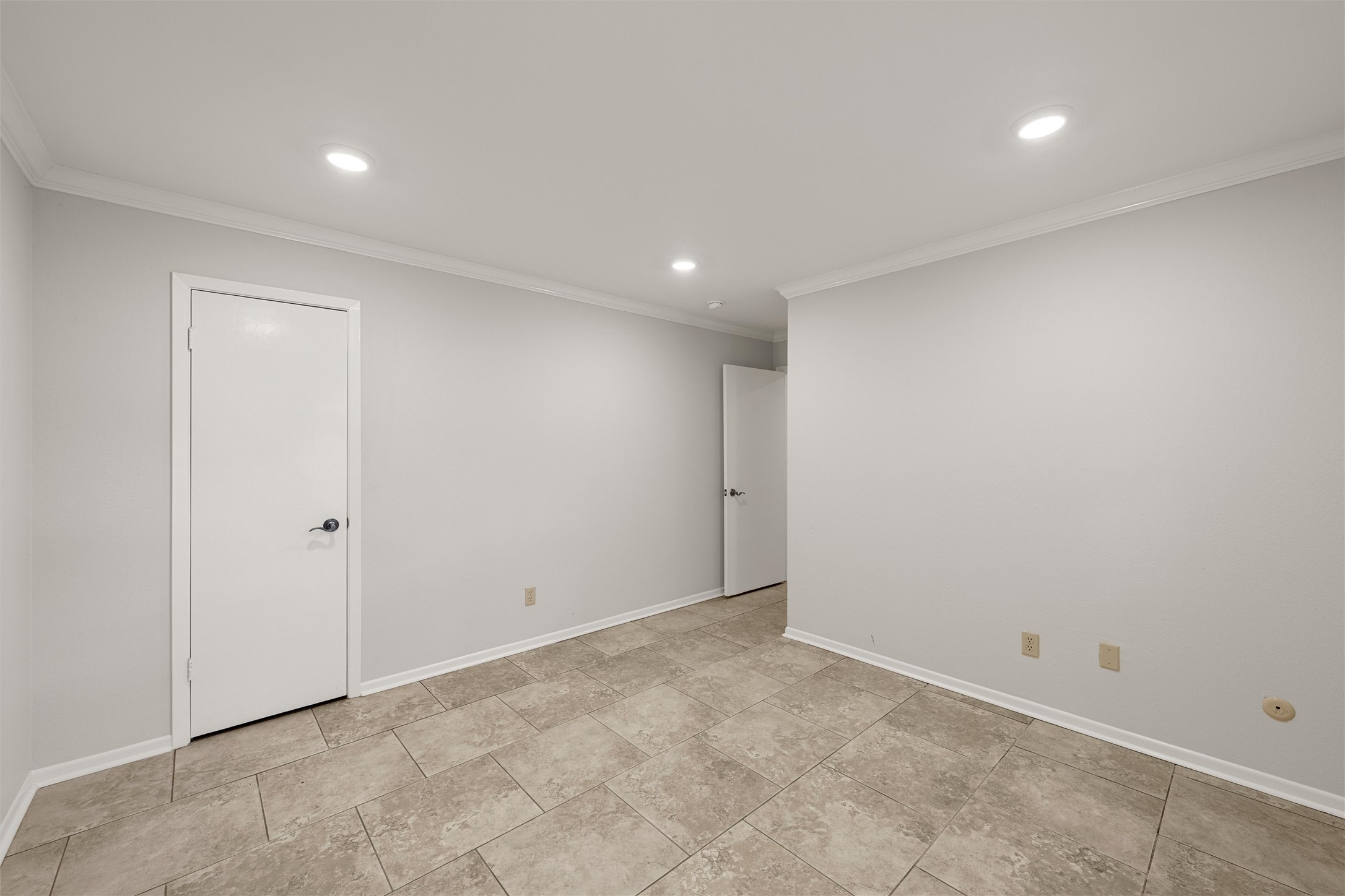 Empty room with beige tile flooring, gray walls, and two white doors.