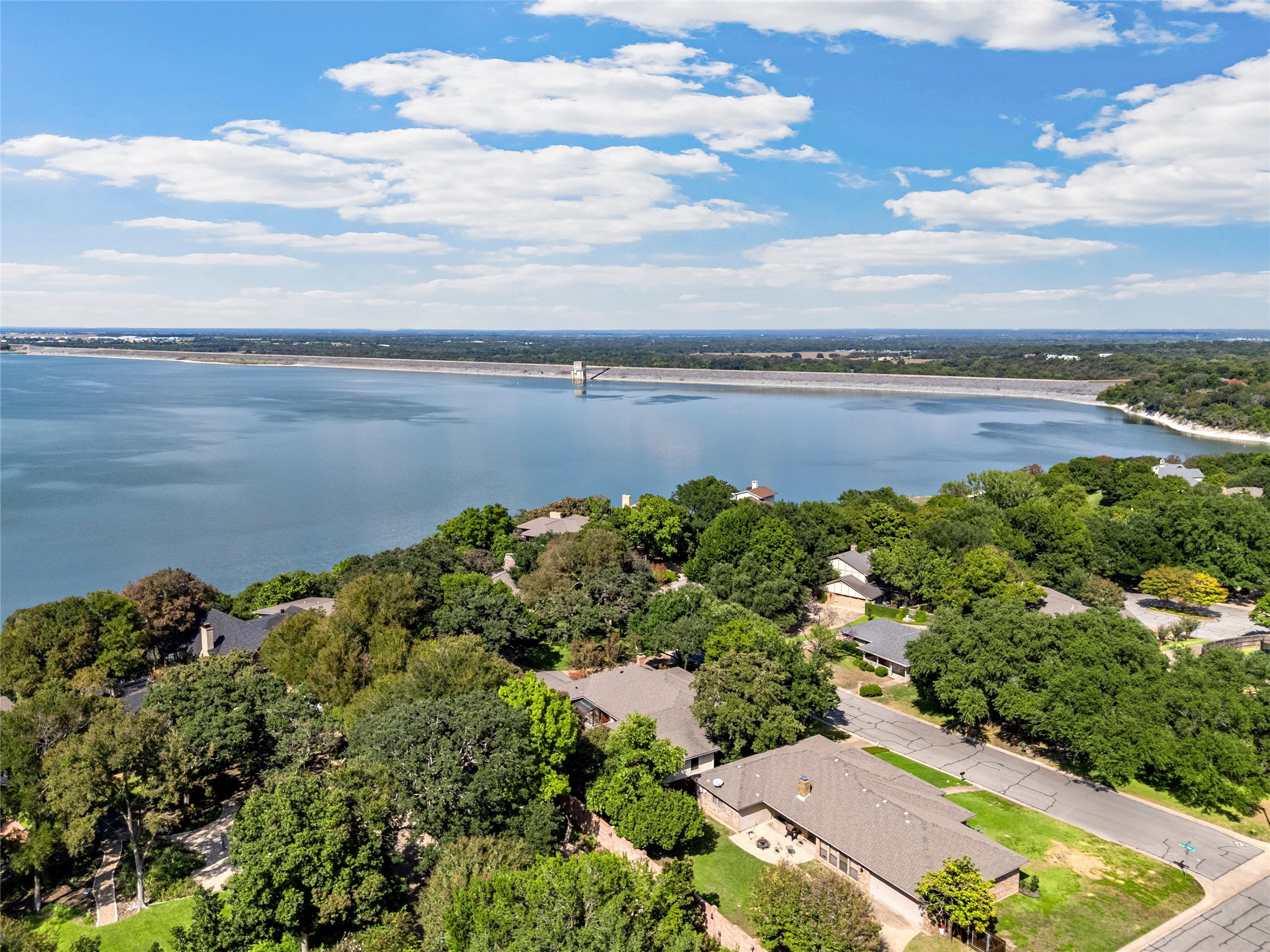 Aerial view of homes among mature trees beside a broad lake.