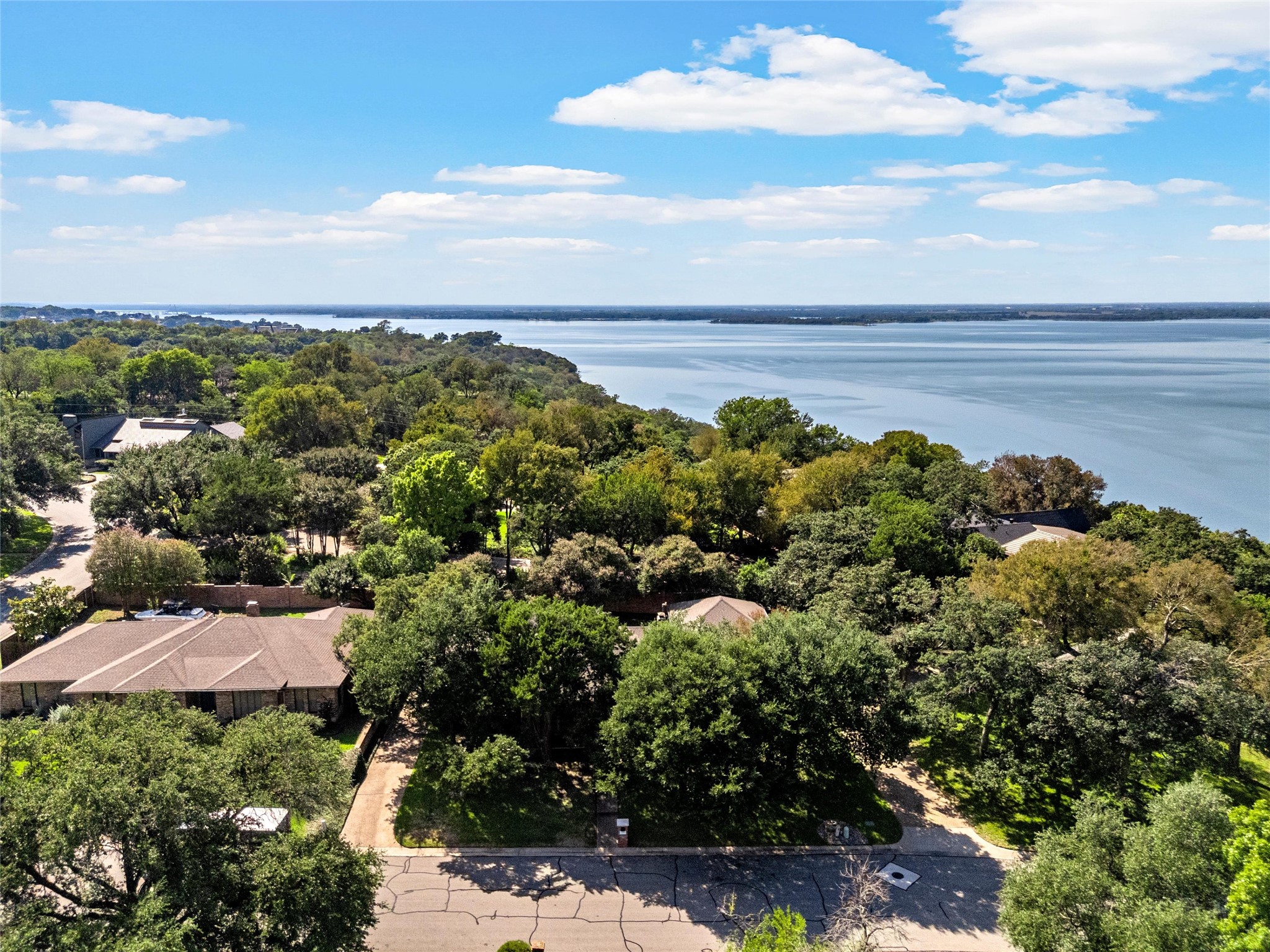 Aerial view of tree-lined homes beside a broad lake.
