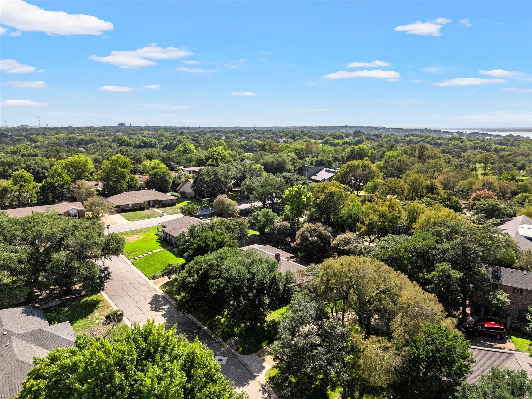 Aerial view of a leafy neighborhood, with tree-lined streets and distant water.