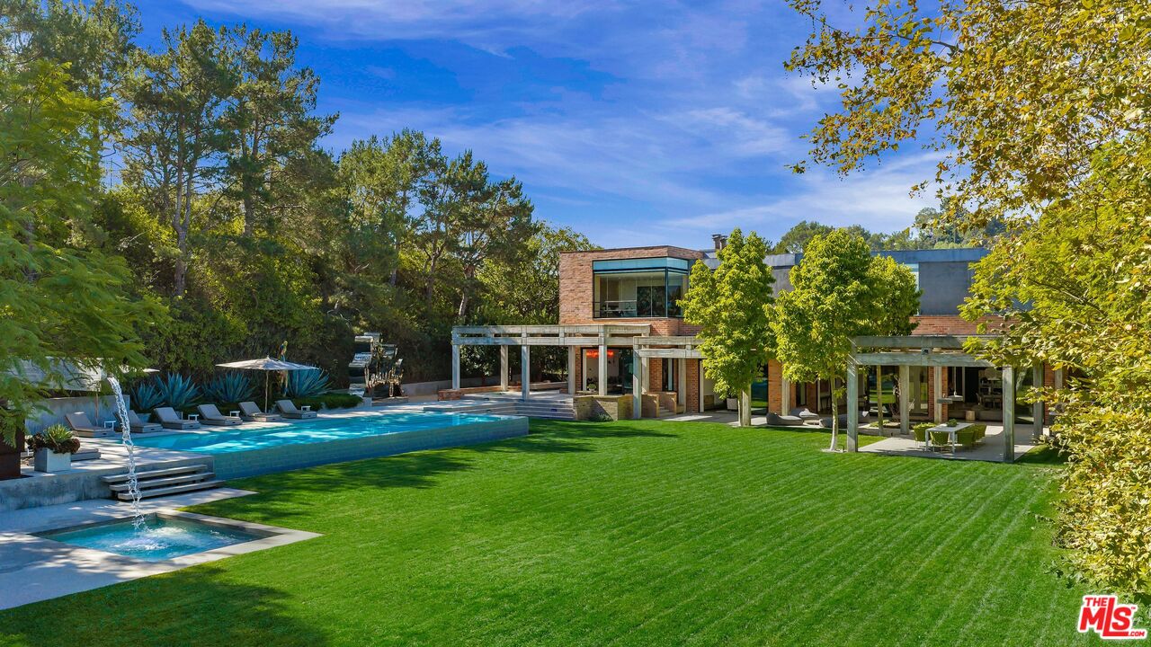Modern two-story home with a pool, spa, and expansive green lawn.