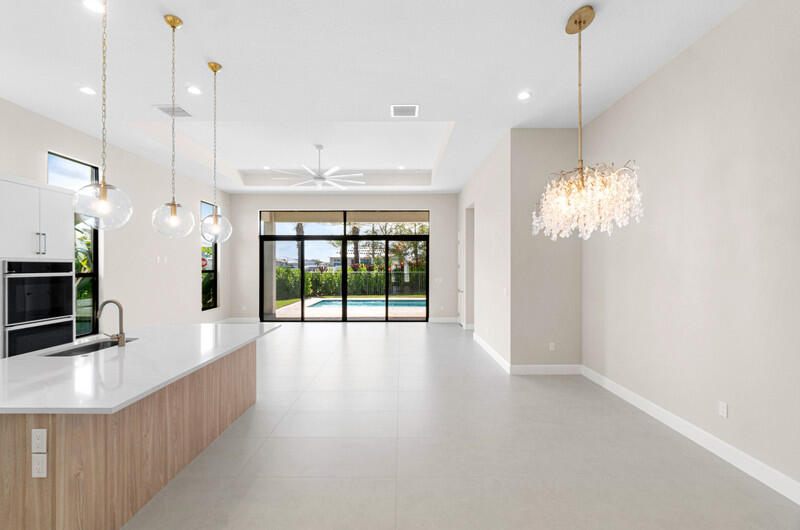 Open-plan kitchen with a white island and sliding doors overlooking a backyard pool.
