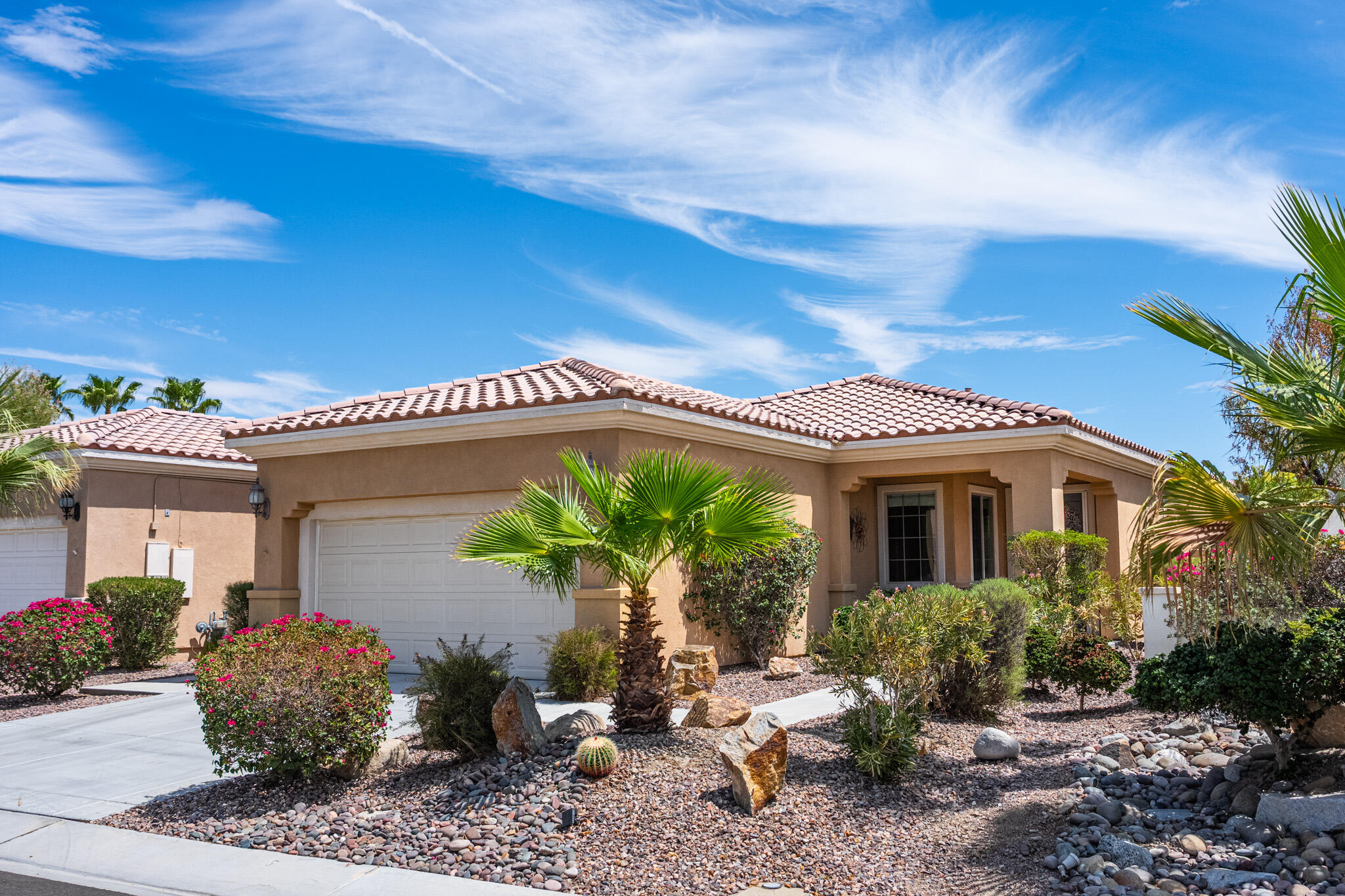 Single-story stucco home with a tile roof, attached garage, and desert landscaping.