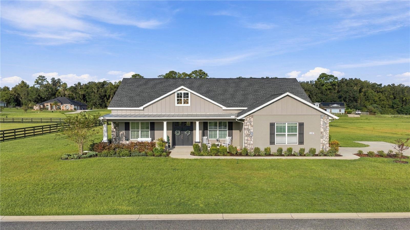 Single-story house with stone accents, a covered porch, and a broad green lawn.