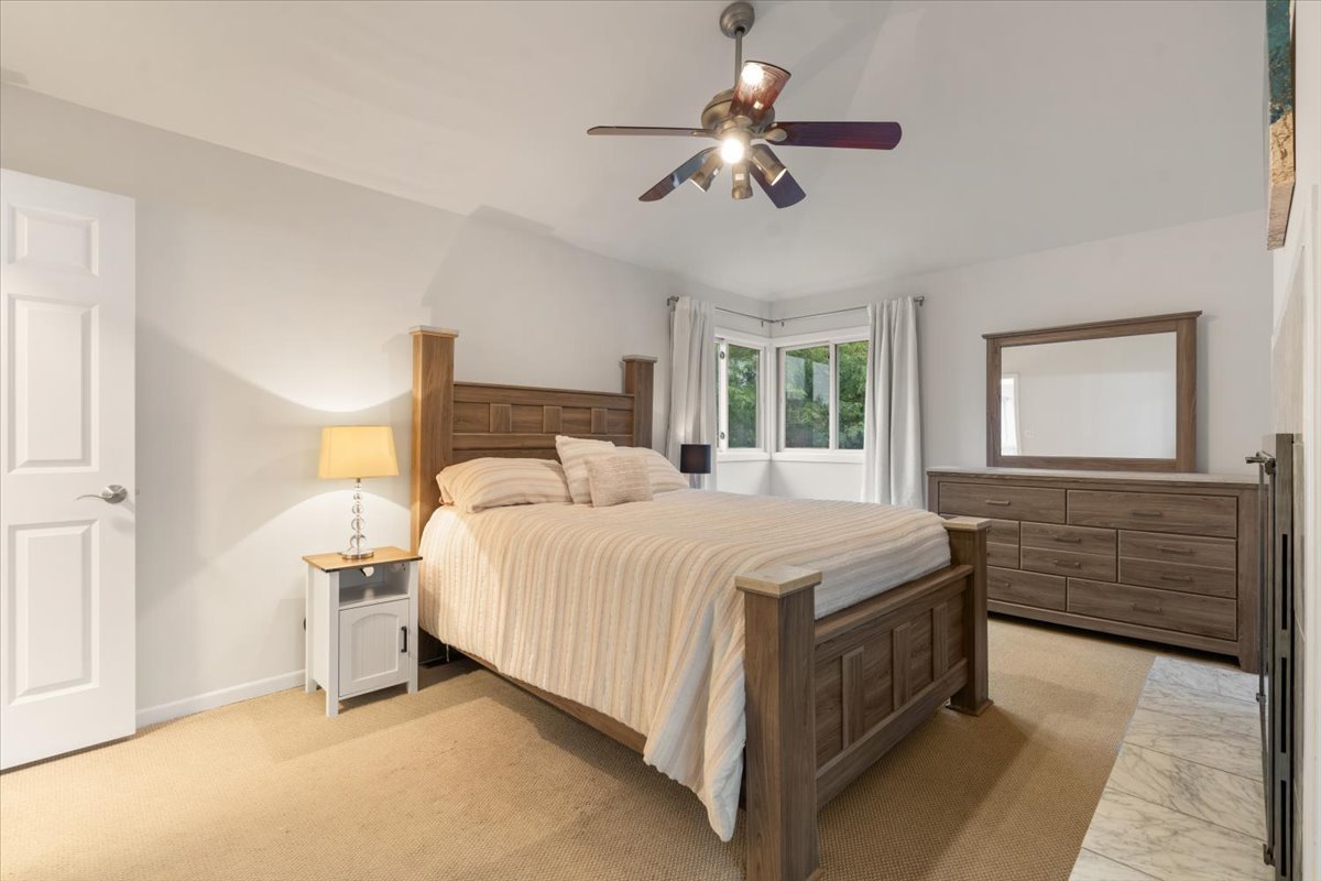 Bedroom with a large wooden bed, matching dresser, and bay windows.