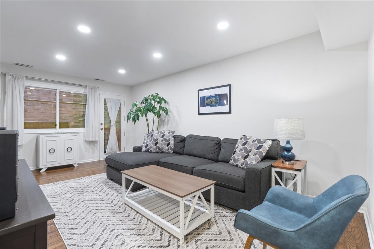 Living room with a gray sectional, blue accent chair, and large curtained windows.