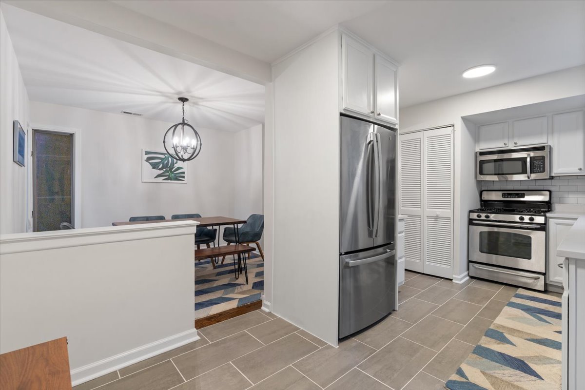 Open kitchen and dining area with stainless steel appliances and a table with blue chairs.