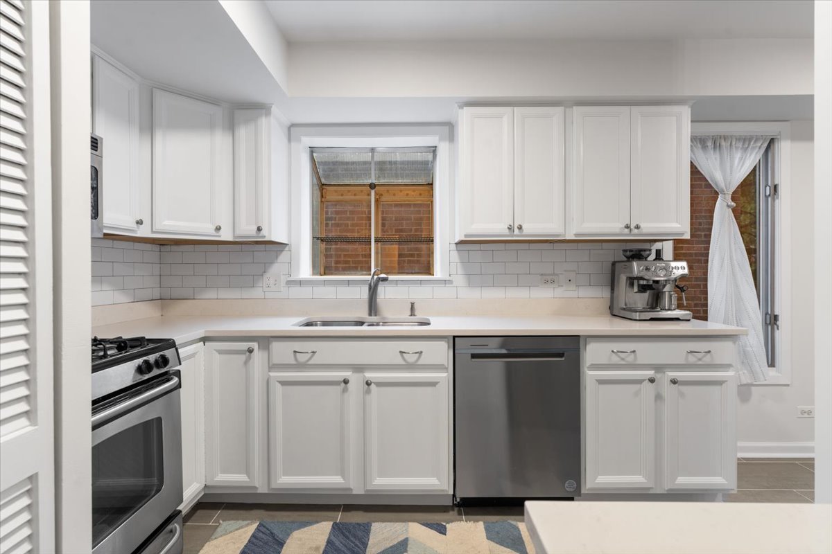 Kitchen with white cabinetry, subway tile backsplash, stainless steel appliances, and a sink beneath a window.