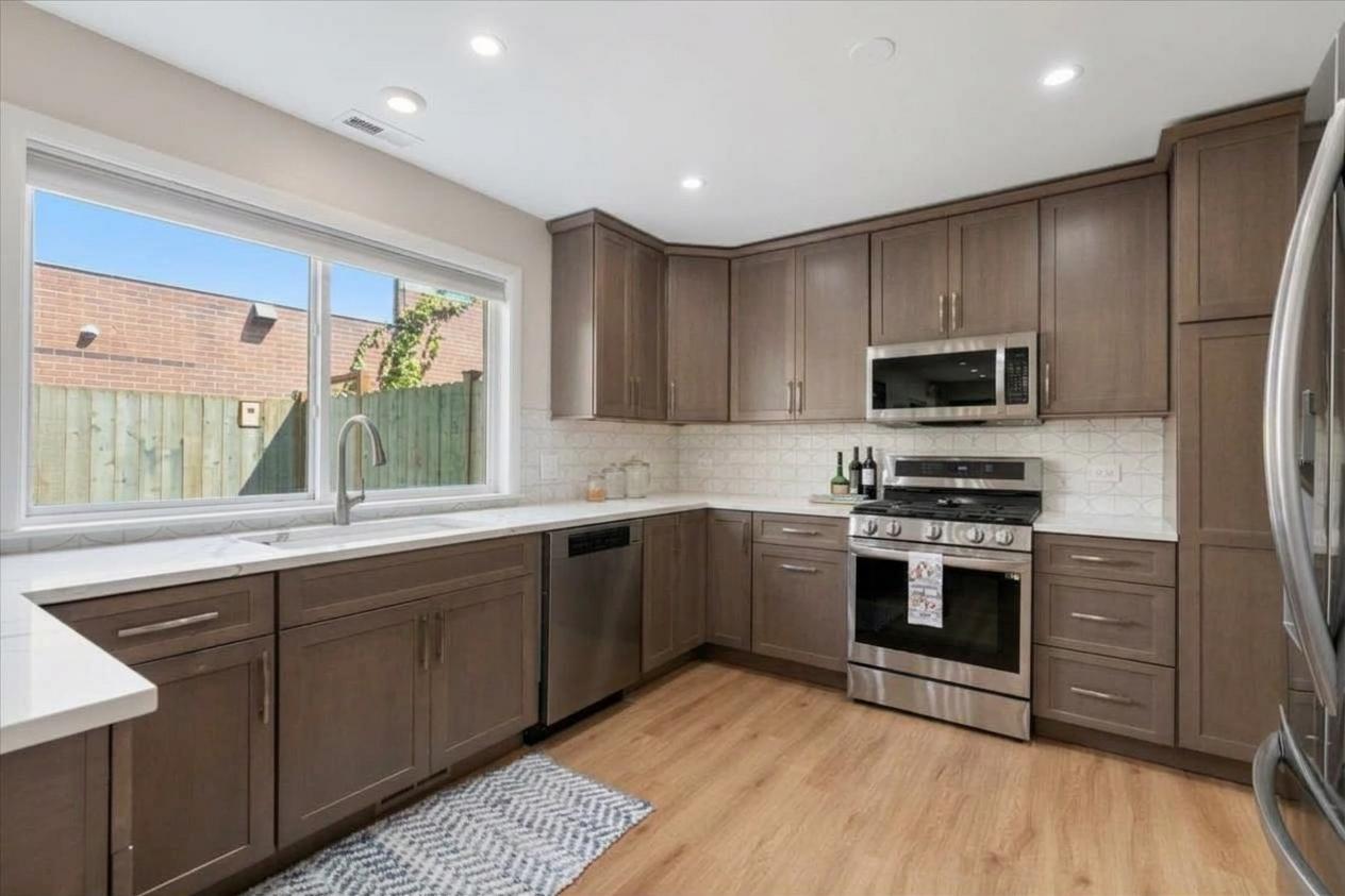 Kitchen with dark wood cabinets, stainless steel appliances, and a large window above the sink.