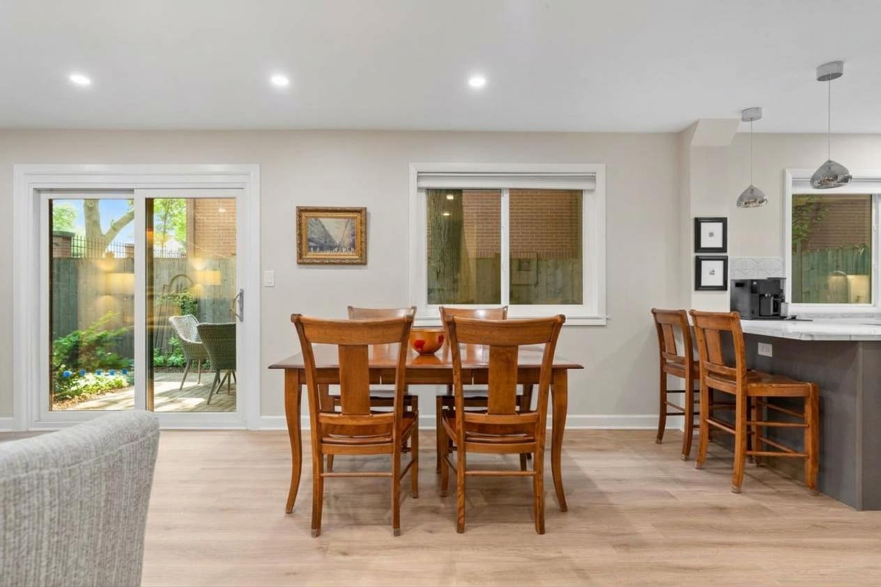 Dining area with a wooden table and chairs beside a kitchen breakfast bar and garden-facing sliding doors.