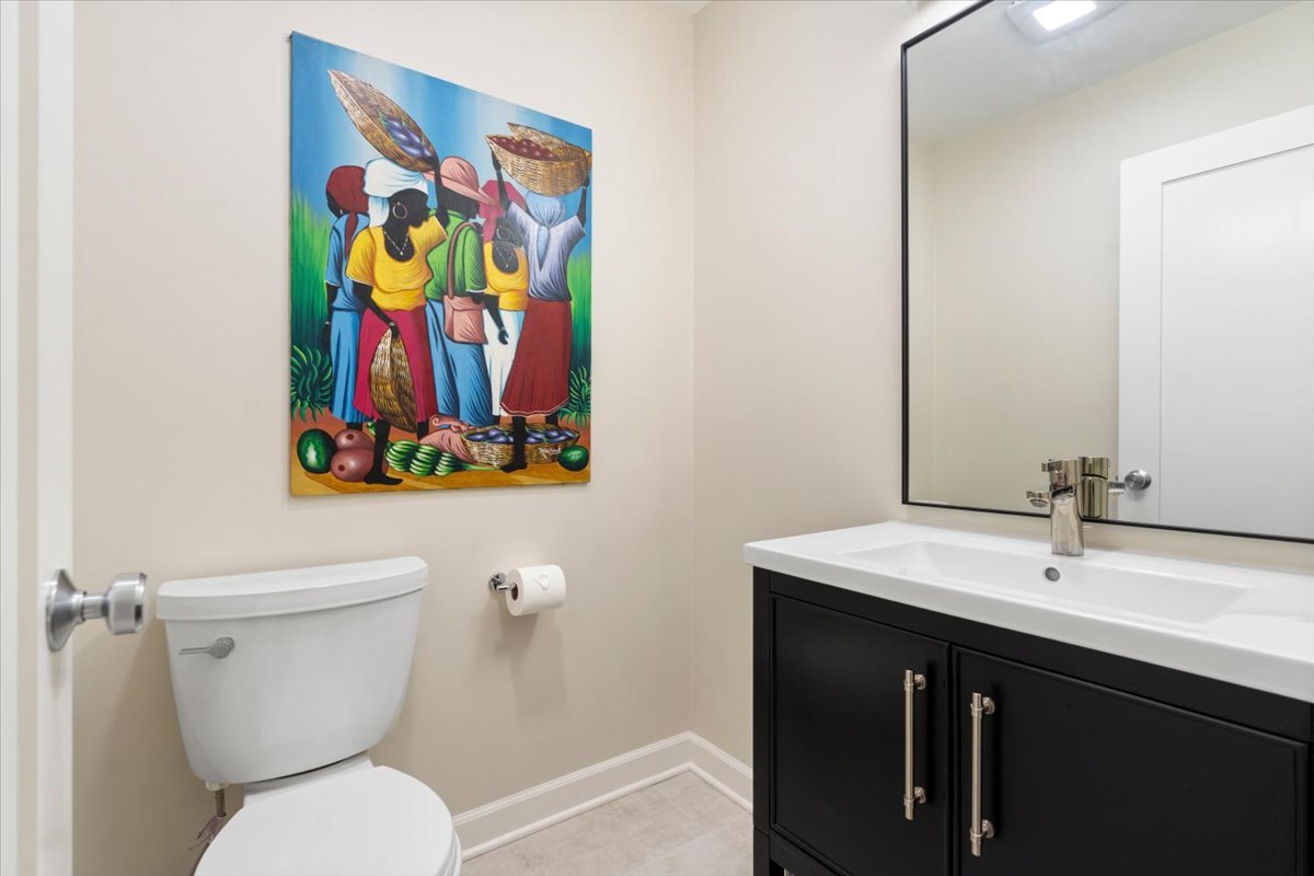 Bathroom with a black vanity, large mirror, and colorful artwork above the toilet.