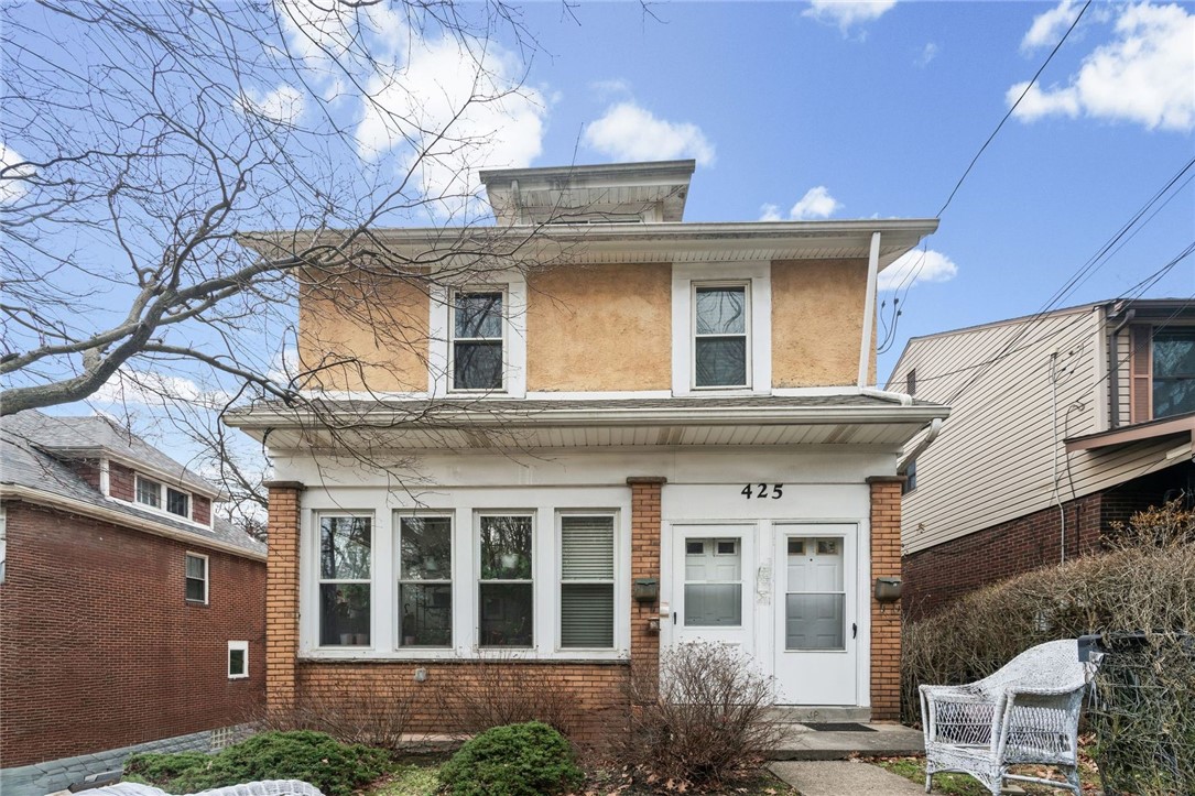 Two-story tan and brick house with white trim, numbered 425, beneath bare tree branches.