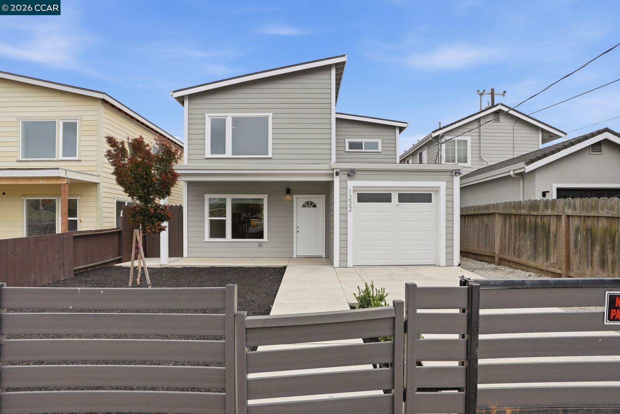 Gray two-story house with white trim and garage behind a gray horizontal-slat fence.