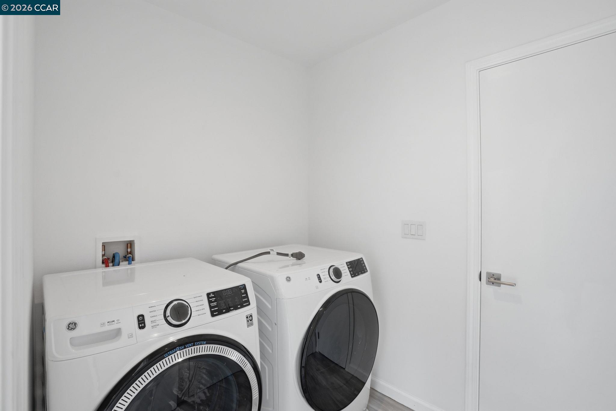 Laundry room with white front-loading washer and dryer beside a white door.