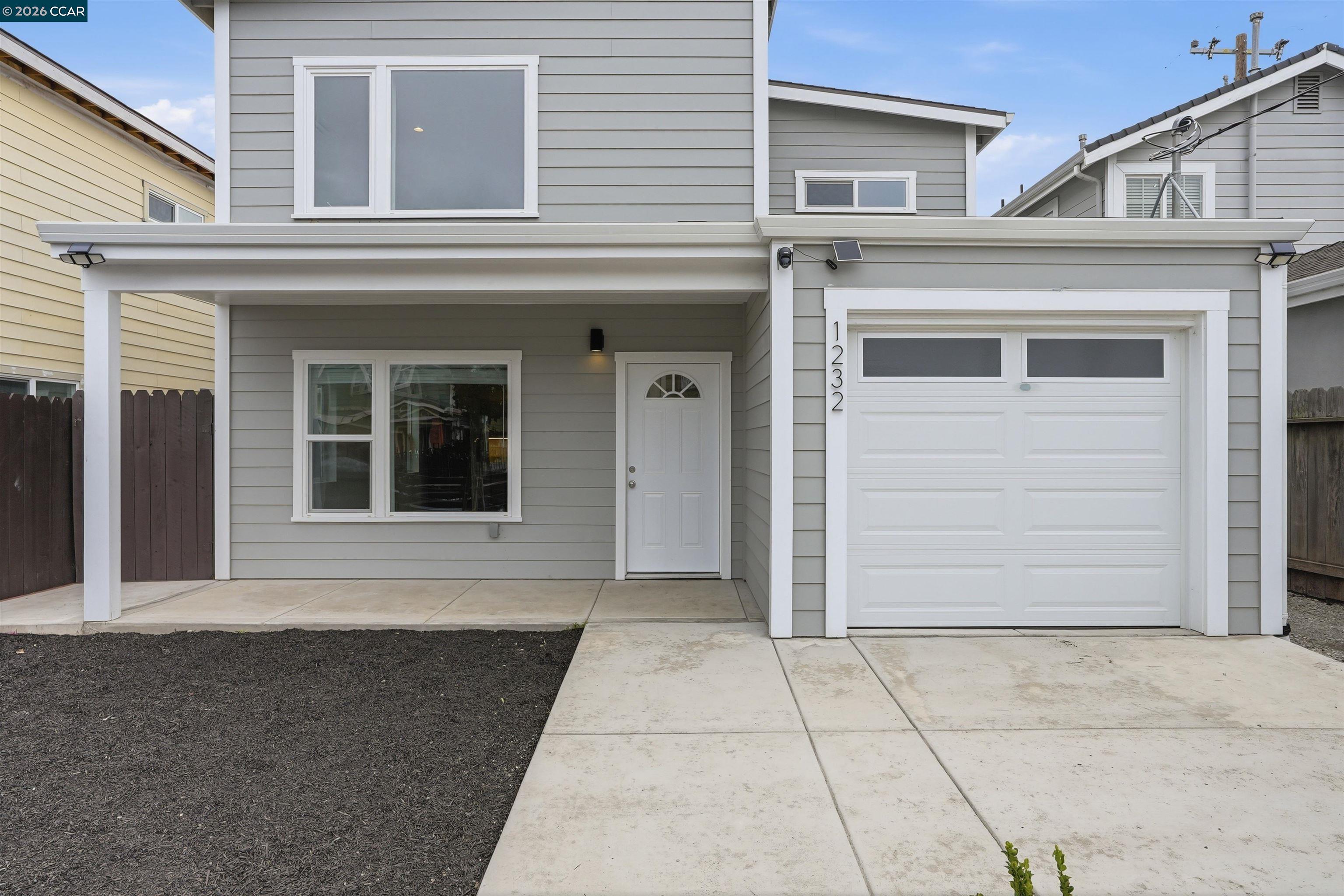 Two-story gray home with white trim, covered front entrance, and attached white garage.