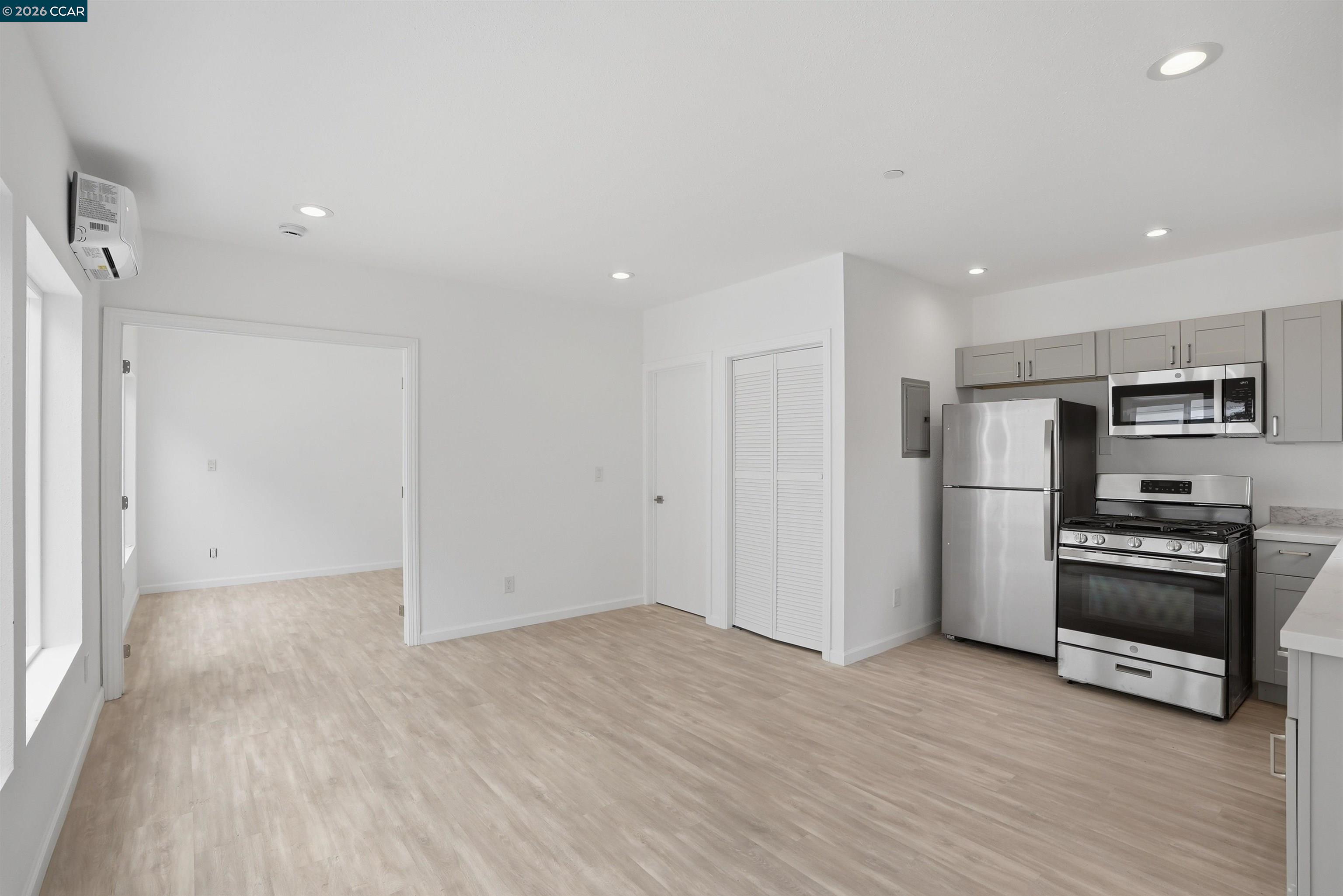 Unfurnished kitchen with gray cabinets, stainless steel appliances, and light wood-look flooring.