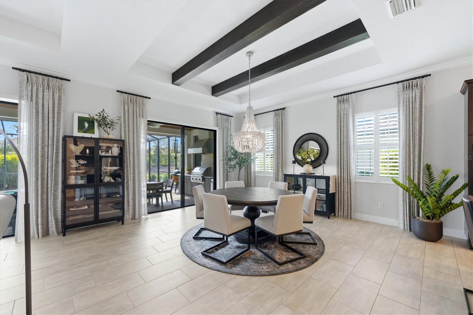 Dining room with dark ceiling beams, a round table, and sliding doors to a covered patio.