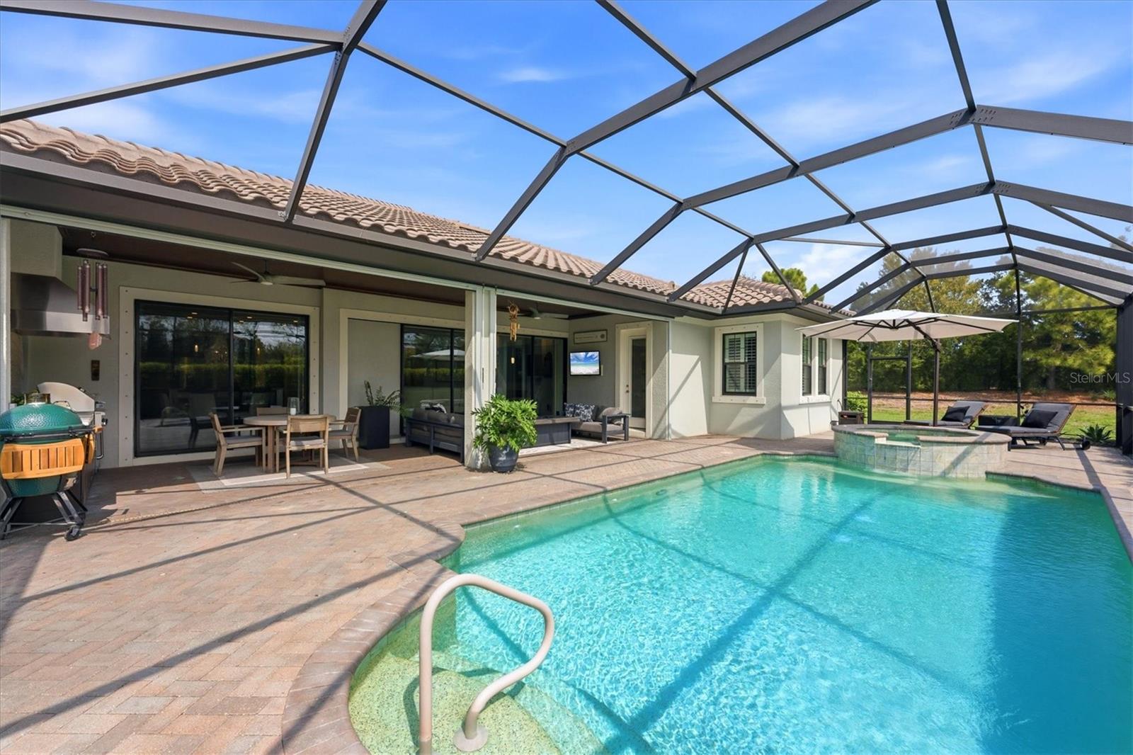 Screened backyard pool and raised spa beside a furnished patio.