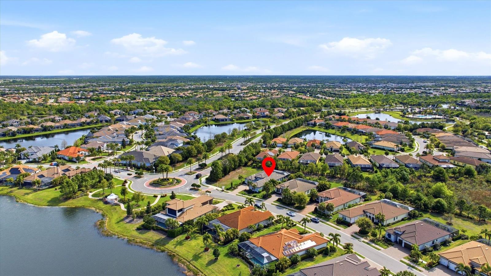 Aerial view of a residential neighborhood with lakes and a red marker identifying the property.