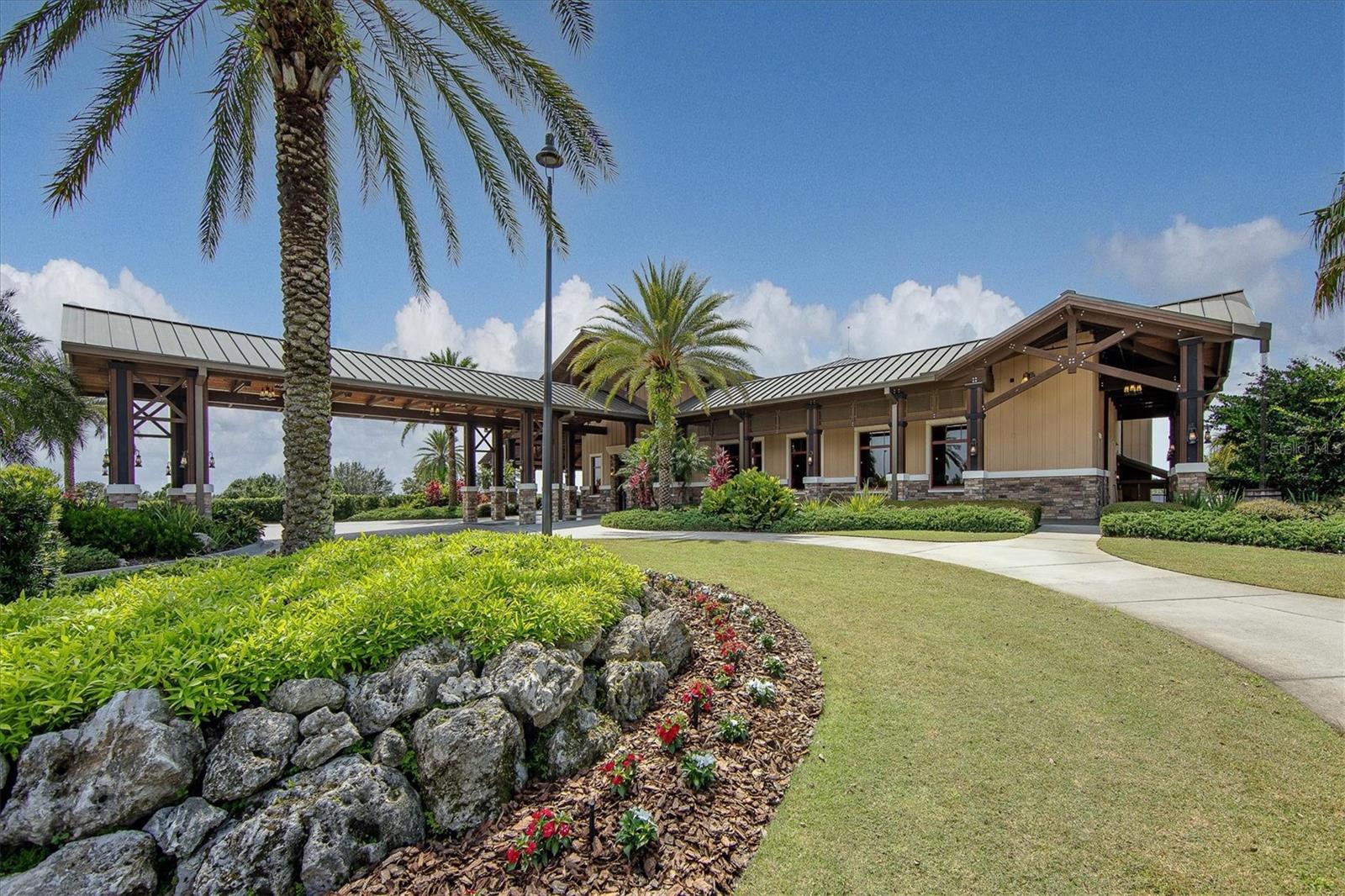 Community clubhouse pavilion with palm trees, landscaped rock garden, and covered entrance.