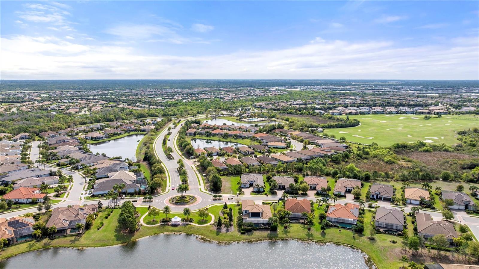 Aerial view of a Lakewood Ranch neighborhood with ponds, a golf course, and a landscaped roundabout.