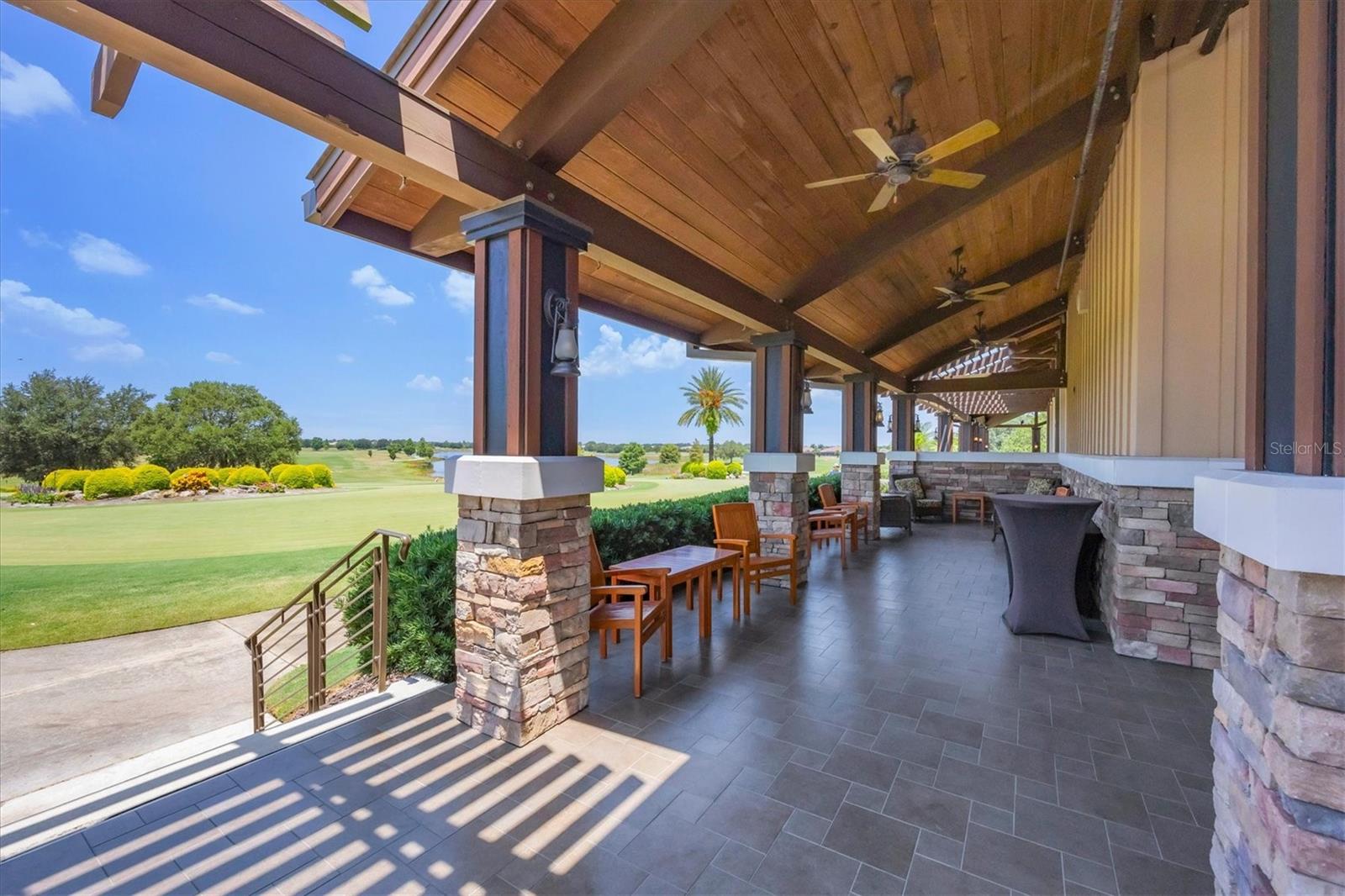 Covered patio with timber ceiling and stone columns overlooking a golf course.