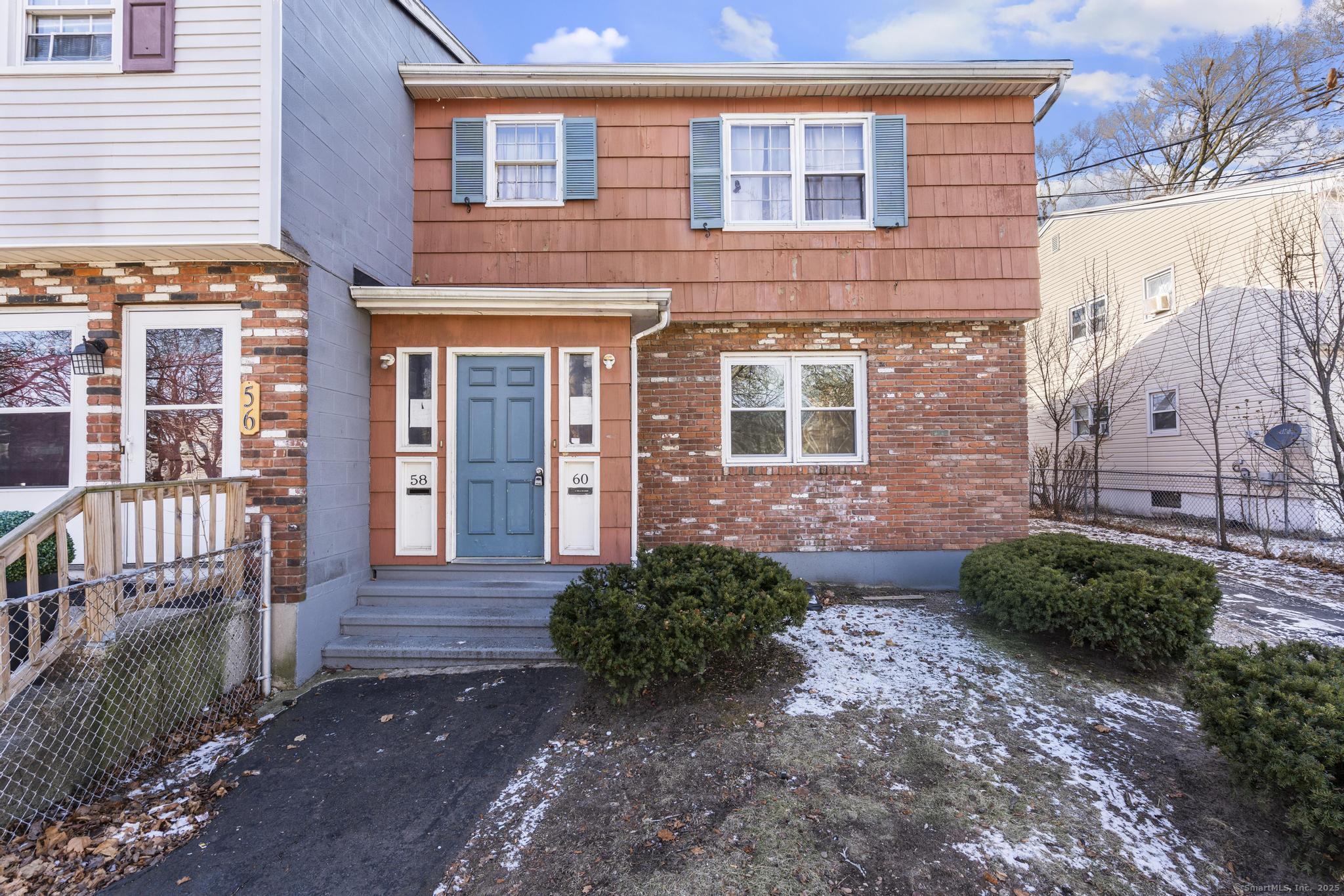 58 Monroe Street exterior with salmon siding, brick facade, blue door, and snow-dusted yard.