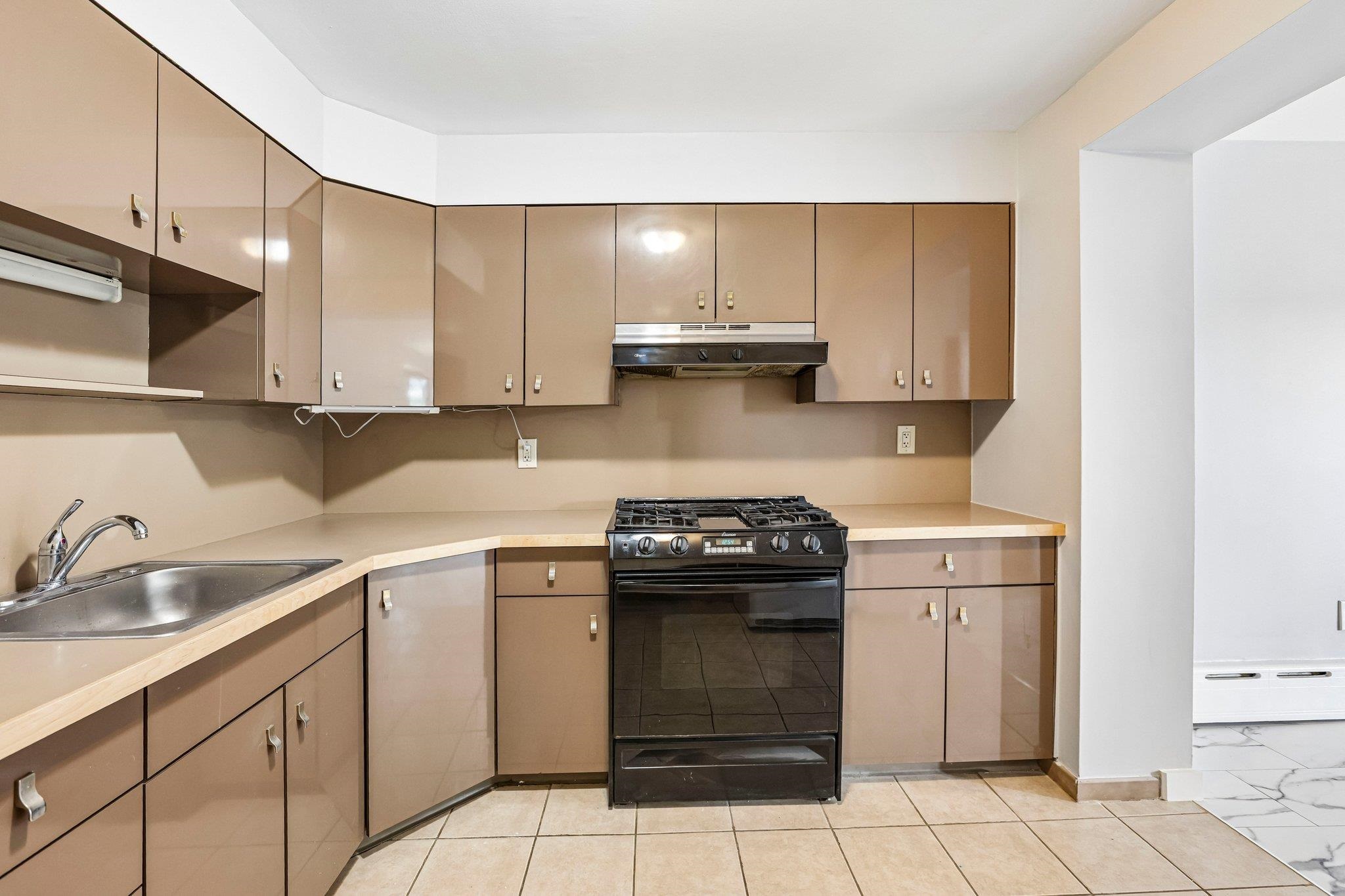 Kitchen with glossy taupe cabinets, a black gas range, and a stainless-steel sink.