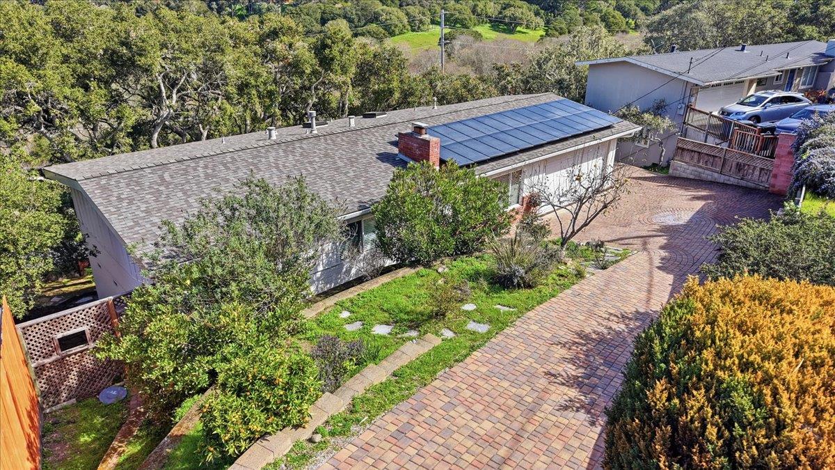 Single-story home with rooftop solar panels and a broad brick-paved driveway.