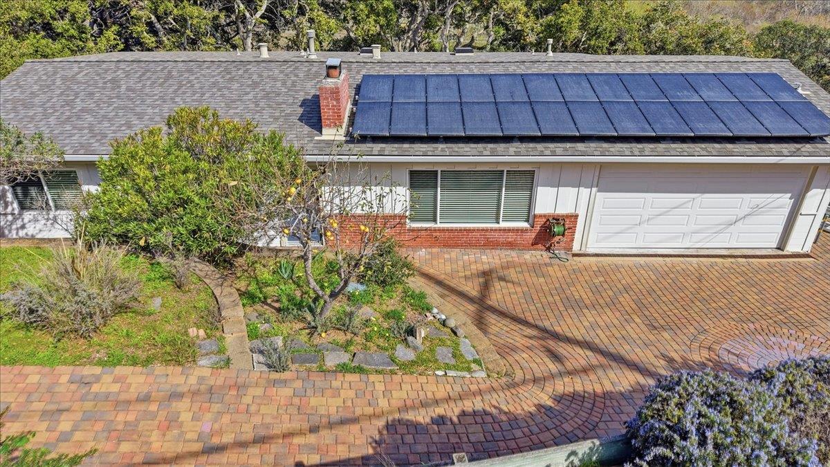 Single-story home with rooftop solar panels, a double garage, and a curved brick-paver driveway.