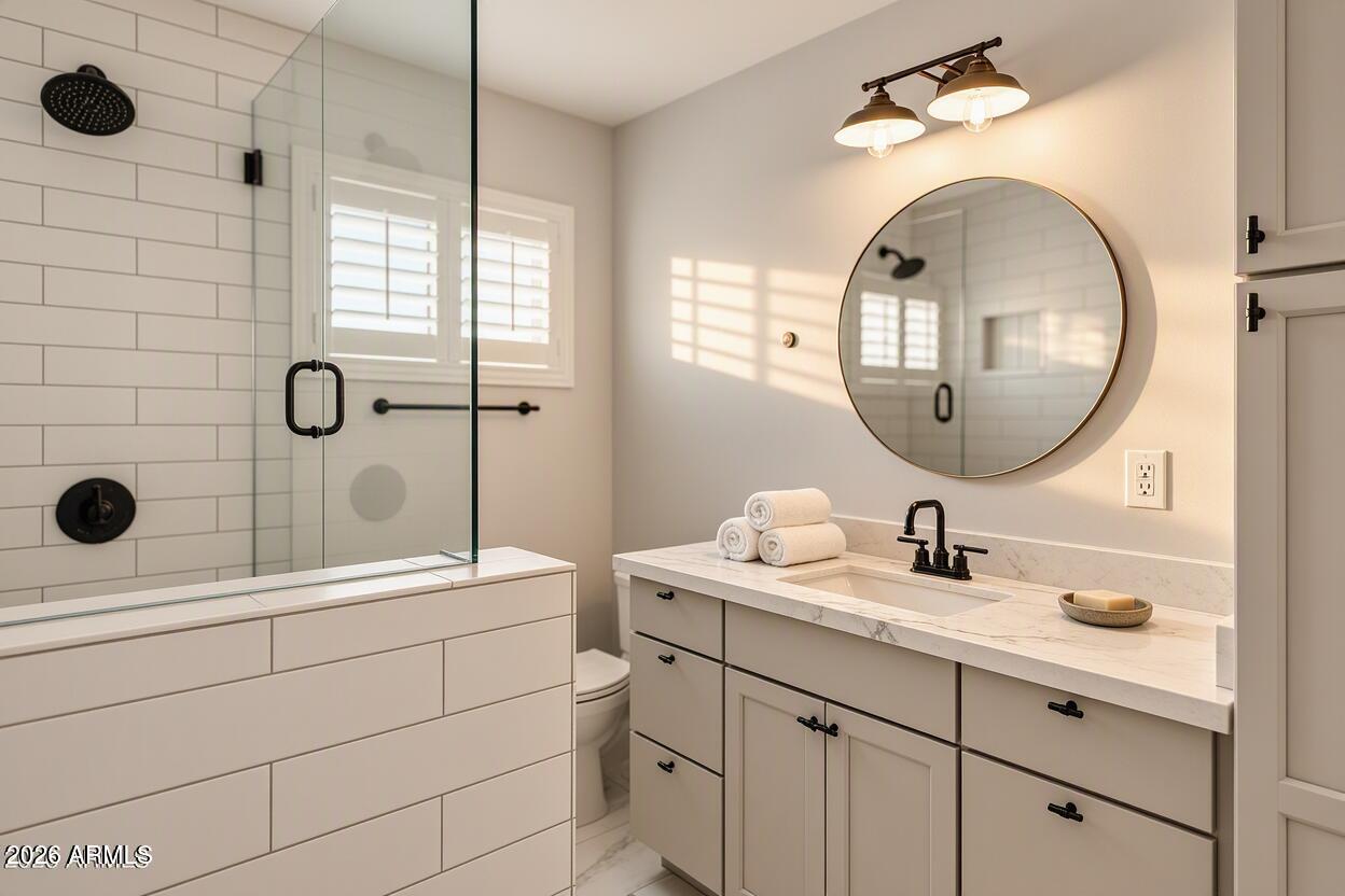 Bathroom with a glass-enclosed subway-tile shower and a marble-topped vanity beneath a round mirror.