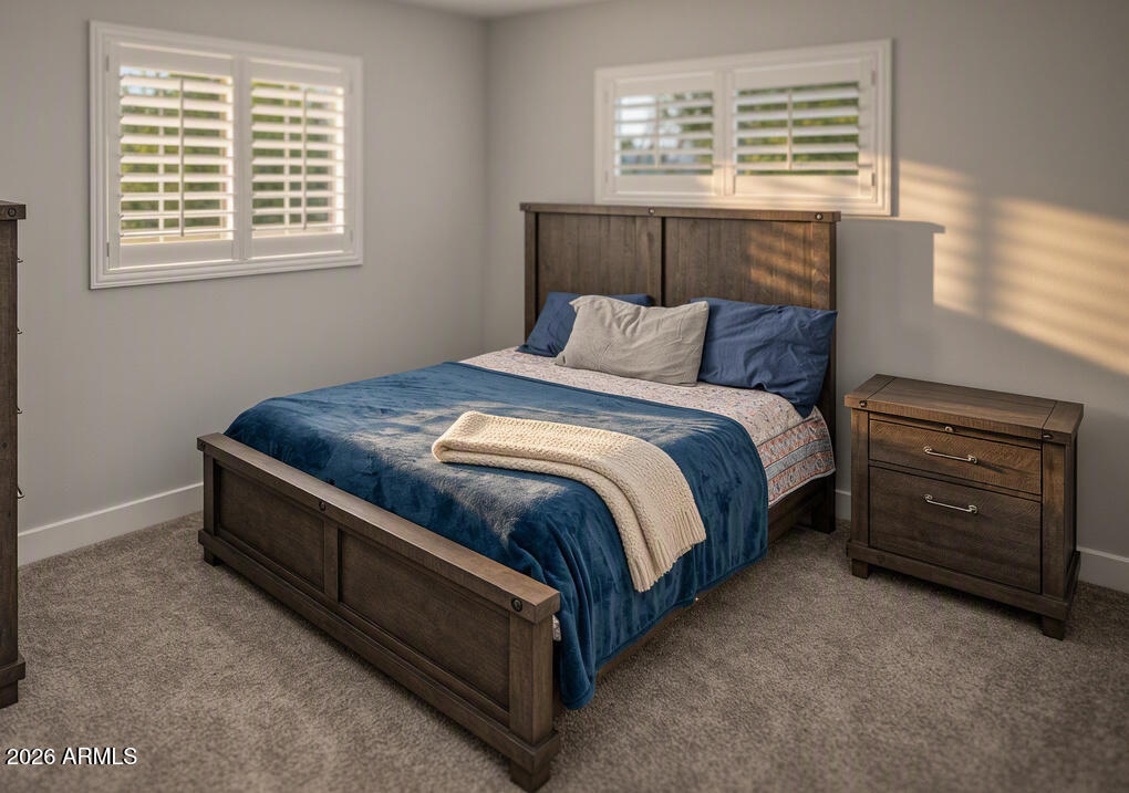 Bedroom with a dark wood bed, blue bedding, and white plantation shutters.