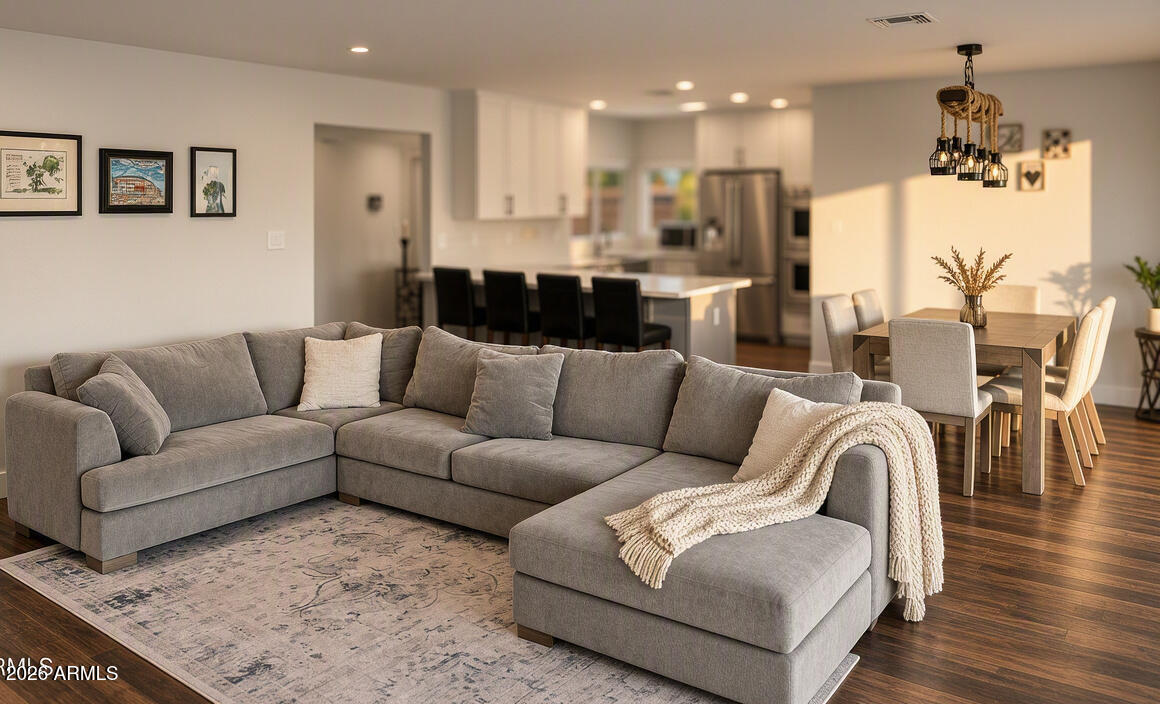 Open-plan living room with a gray sectional and chaise facing a dining area and kitchen.