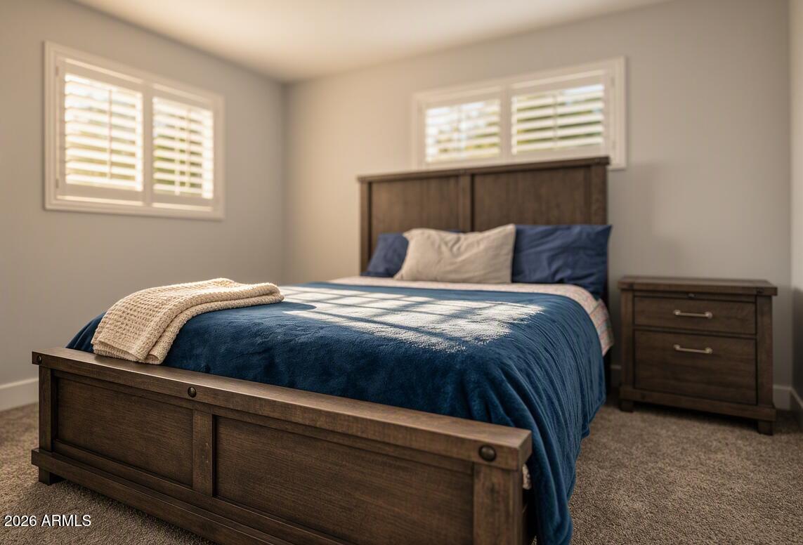 Bedroom with navy bedding, dark wood furniture, and plantation shutters.