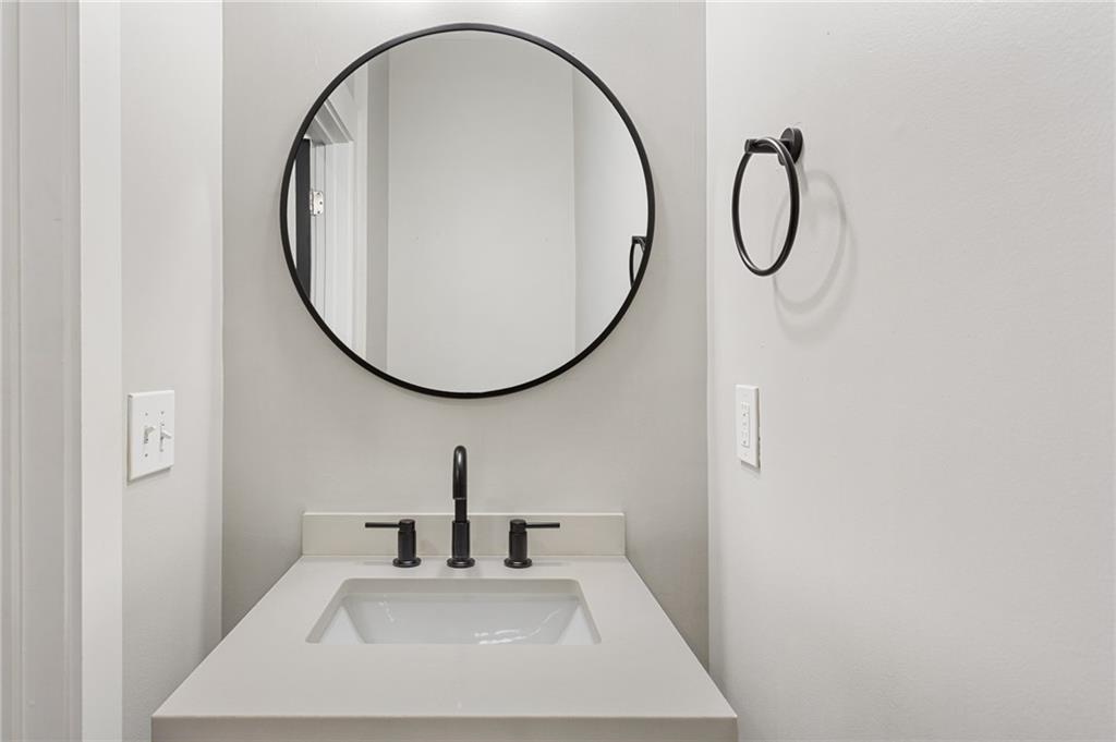 Bathroom vanity with a white sink, black fixtures, and a round black-framed mirror.