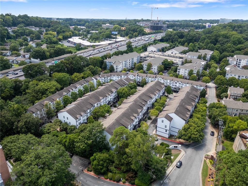 Aerial view of a tree-lined residential complex beside a busy highway.