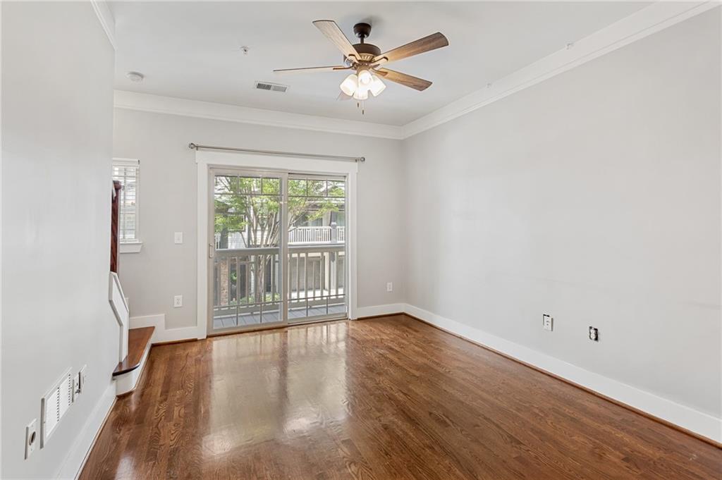 Empty room with hardwood floors, a ceiling fan, and sliding glass doors opening to a balcony.