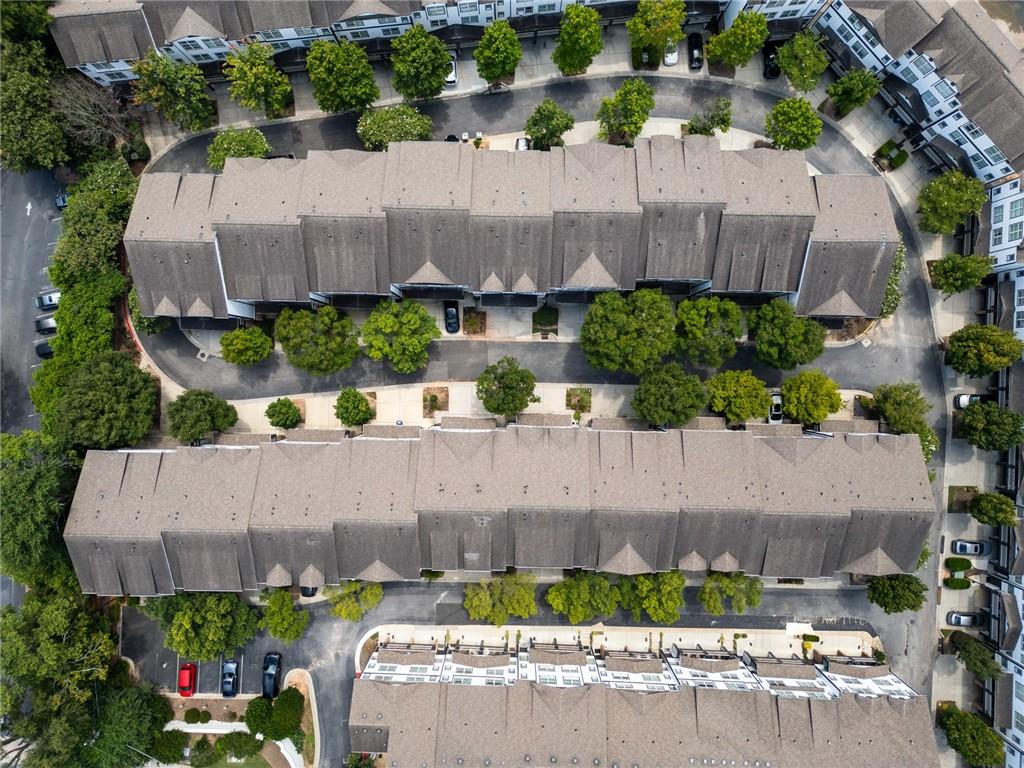 Aerial view of attached condominium buildings surrounded by trees and driveways.