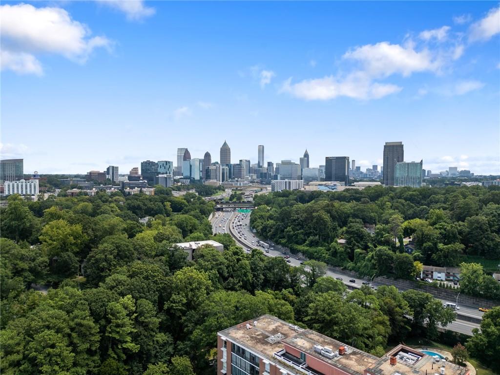 Aerial view of Atlanta’s skyline beyond wooded neighborhoods and a highway.