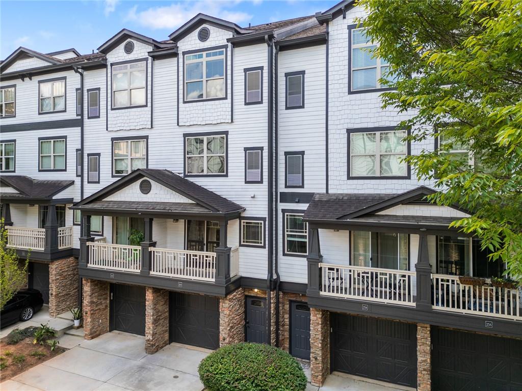 Attached townhomes with white siding, covered balconies, stone accents, and front-entry garages.